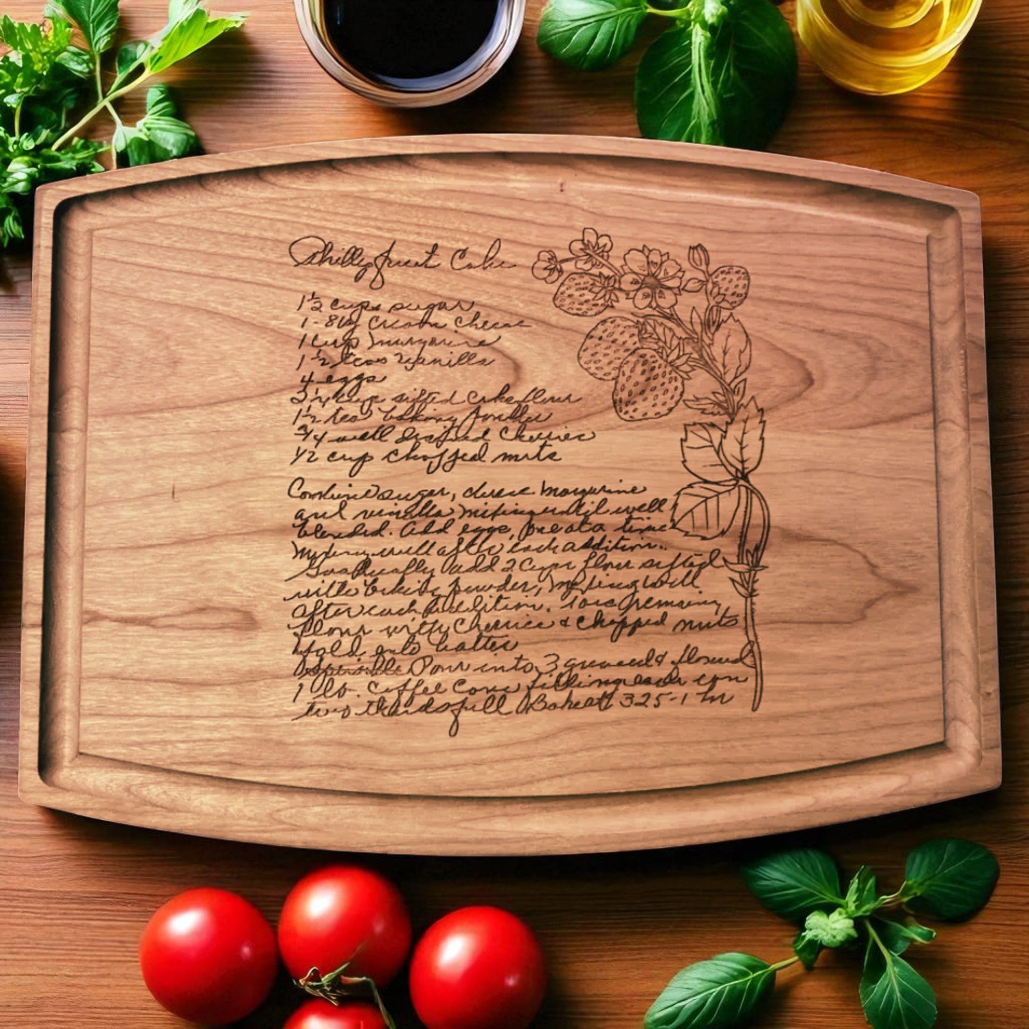 Wooden cutting board with engraved recipe and floral design, surrounded by tomatoes and herbs on a wooden surface.
