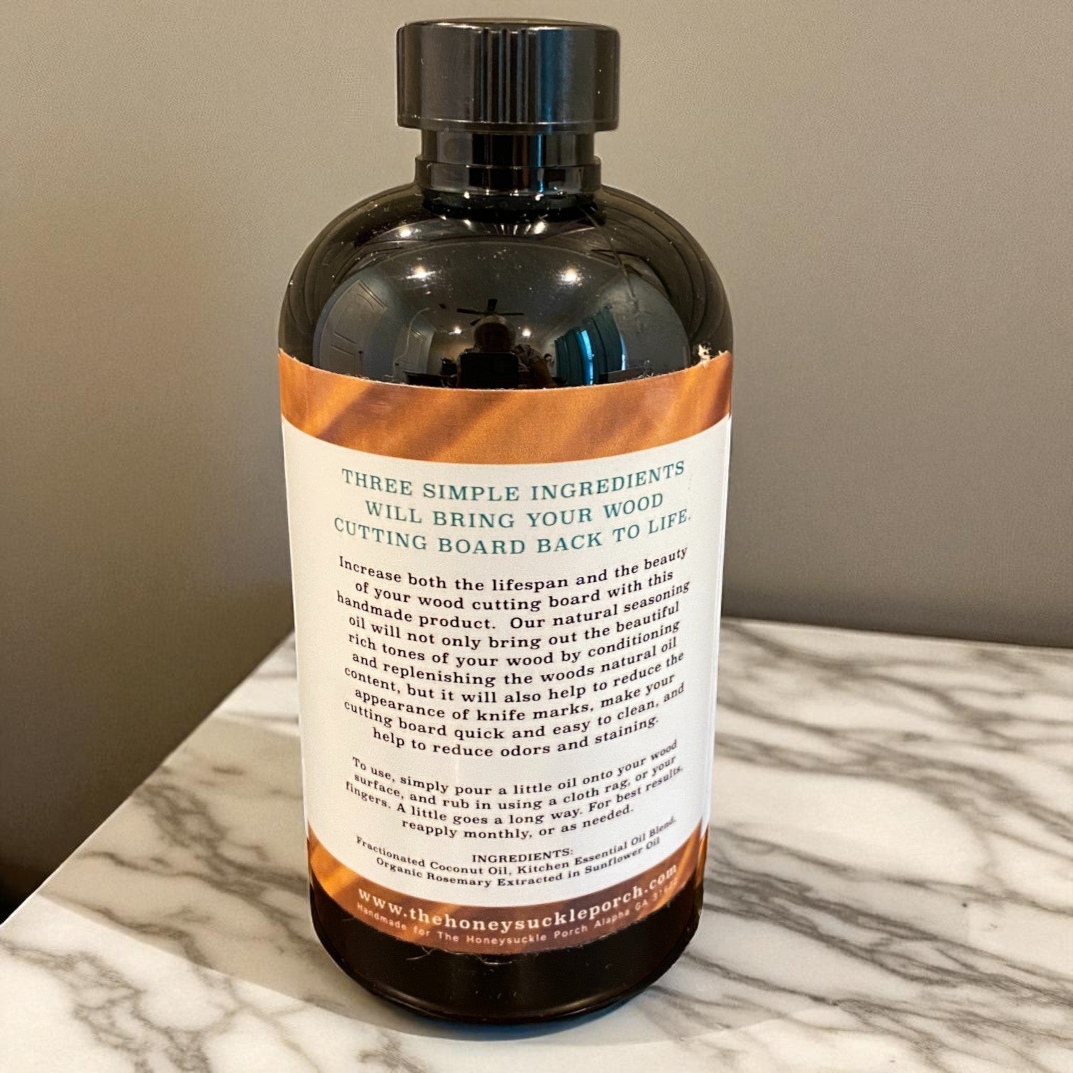 Bottle of all natural cutting board oil with label showing ingredients on a marble surface