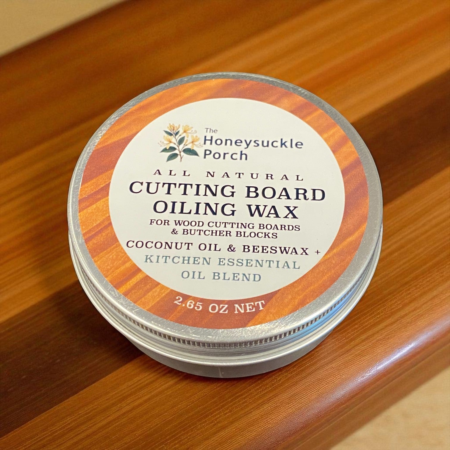 Tin of Honeysuckle Porch cutting board oiling wax on a wooden surface