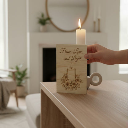 Greeting card with candle and poinsettia on table with woman's hand holding it.