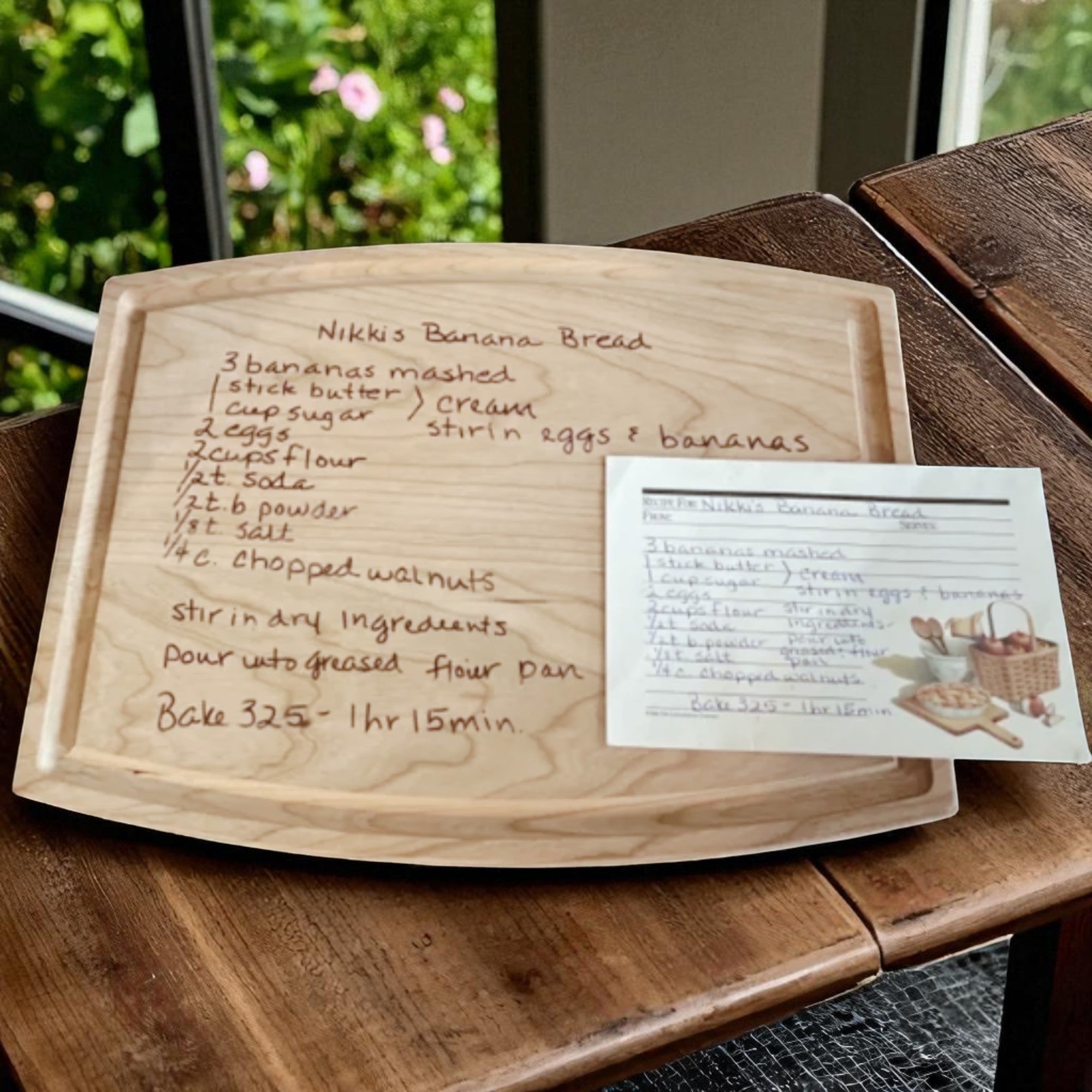 Wooden cutting board with handwritten recipe for banana bread on a wooden table.
