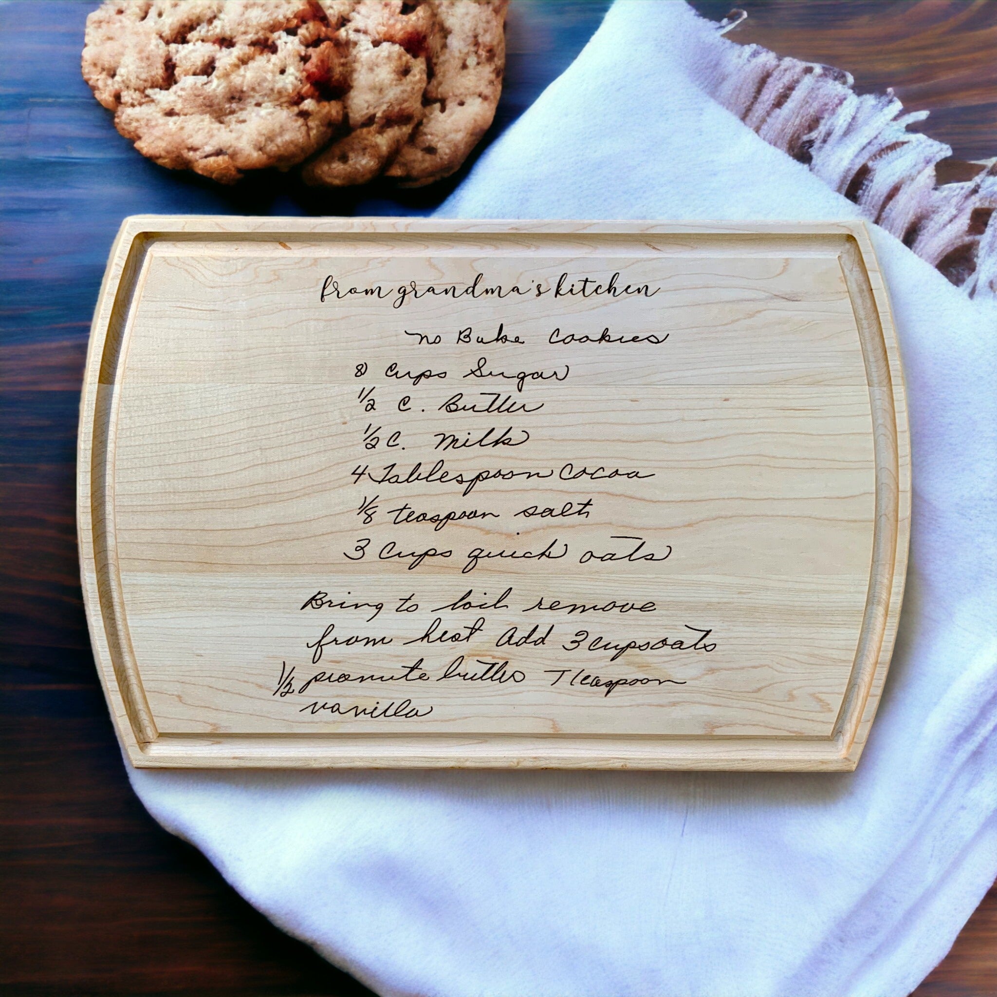 maple cutting board on dish towel with handwritten recipe for no bake cookies